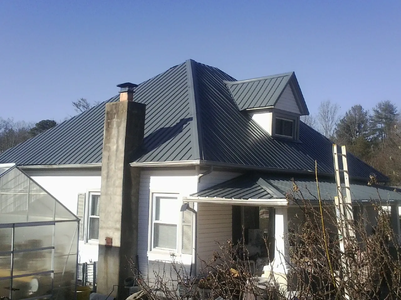 Dark blue standing seam metal roof on a white farmhouse with dormer — Slate & Tile Roof Repair by Roofing Brothers in Lenhartsville