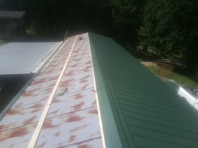 Old rusted panels beside newly installed green metal roofing — Wind Damage Roof Repair by Roofing Brothers in Lenhartsville