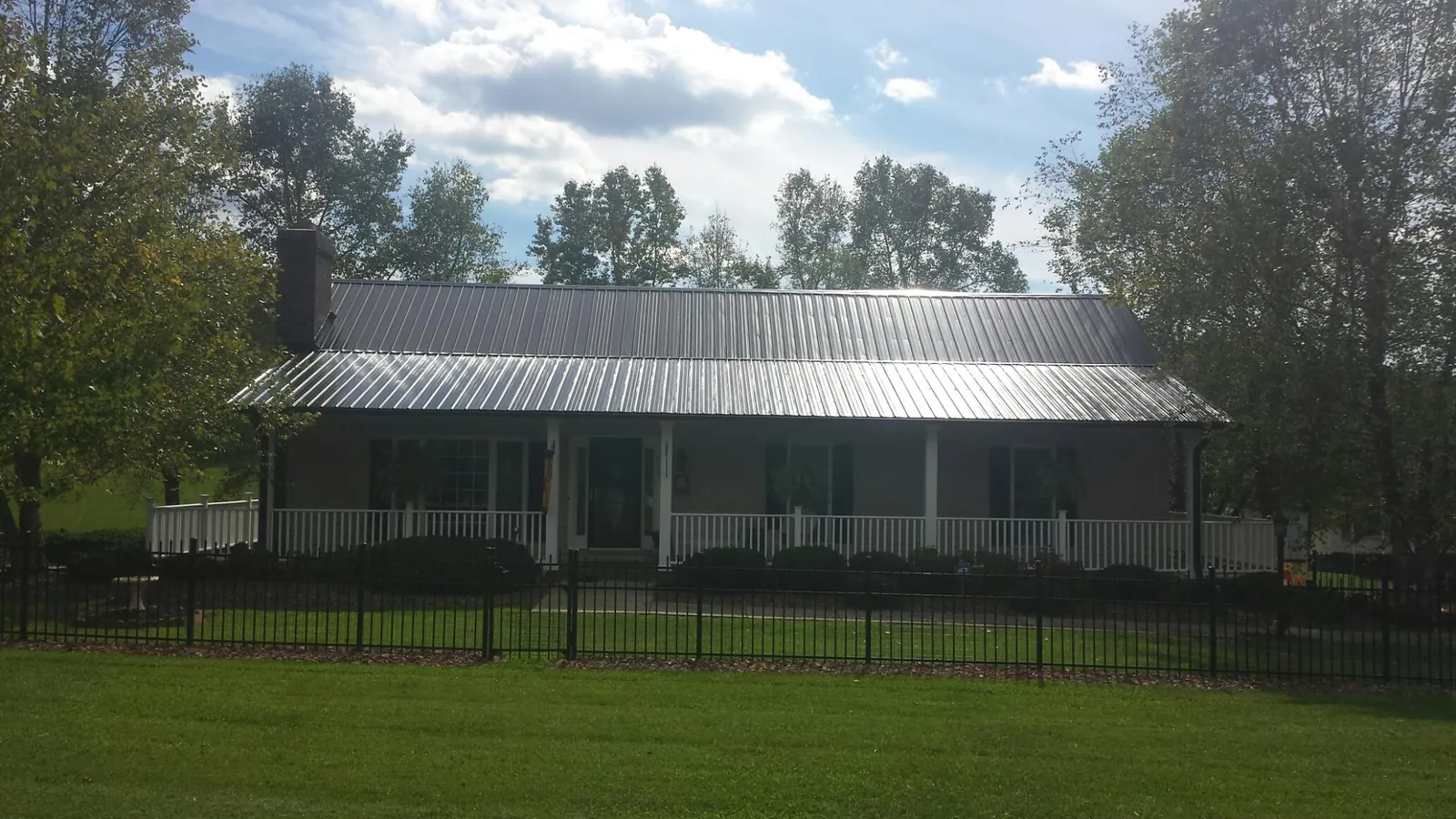 Gray metal roof on a brick ranch with a full width front porch — Gutter Guard Installation work by our crew in Lenhartsville