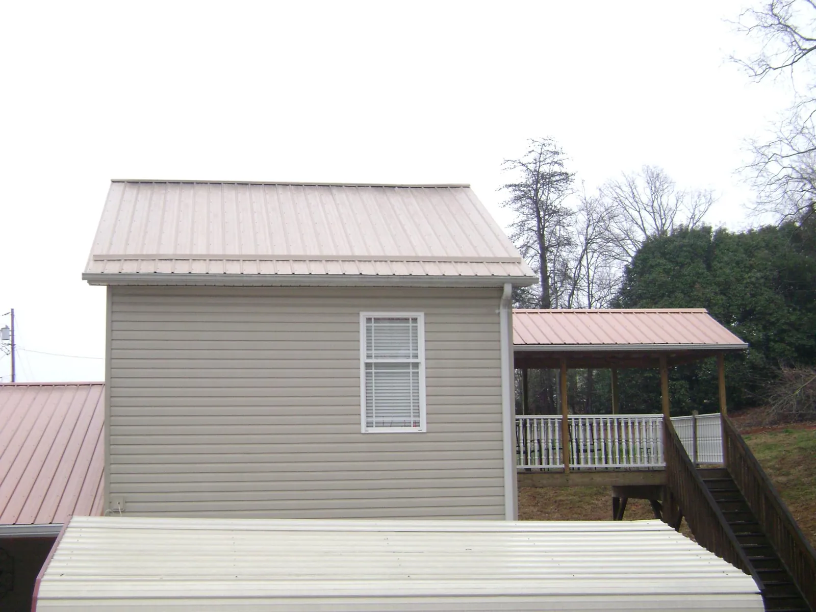 Tan metal roofs on a two story addition and attached porch, from a Roof Replacement job in Lenhartsville