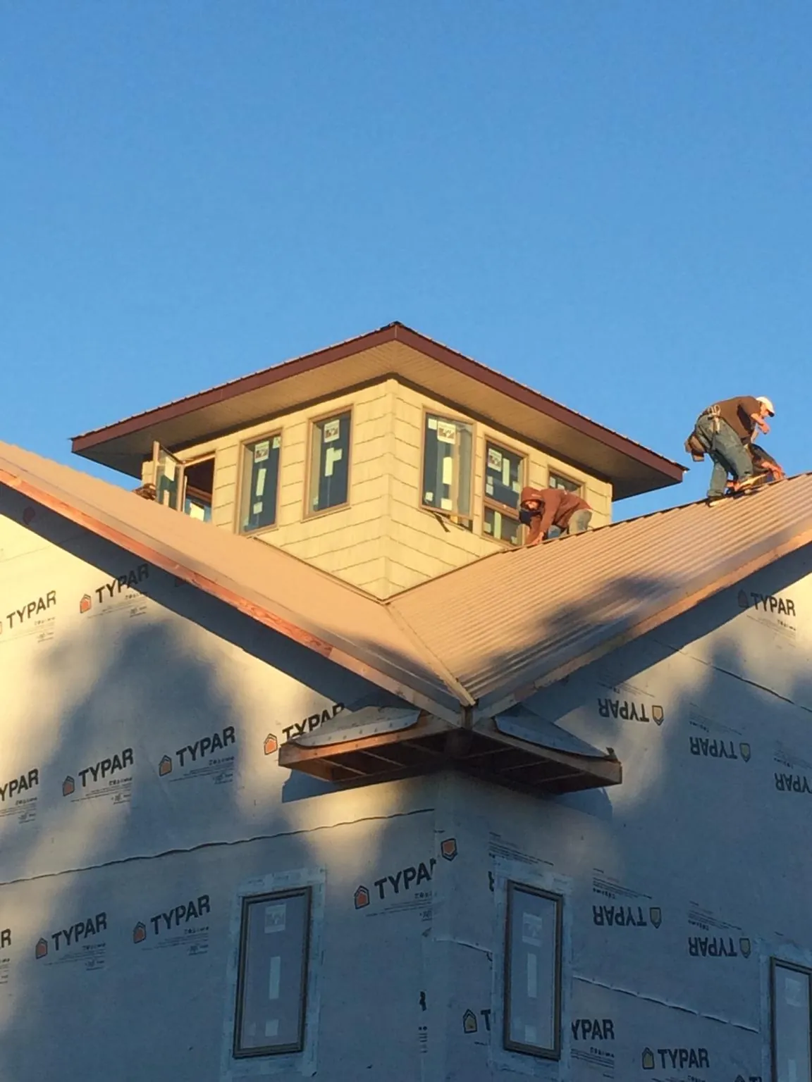 Roofers working around a rooftop cupola on a new metal roof at sunset — Roof Waterproofing in Lenhartsville by Roofing Brothers